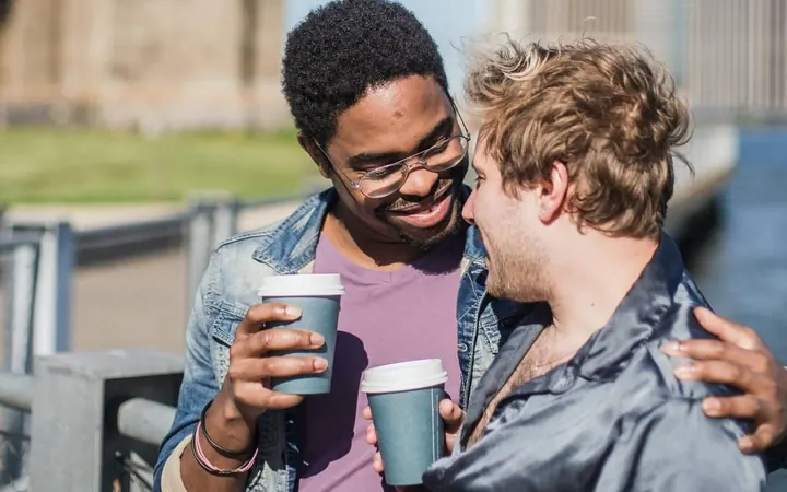 Zwei Männer unterhalten sich lachend bei einem Kaffee